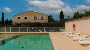 A swimming pool with lounge chairs, a fenced area, and a building with shutters. - Holiday Home Near Lake Saint-cassien (Tourrettes)