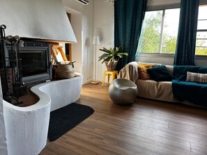 Ein gemütliches Wohnzimmer mit Kamin, einer Couch, einer Topfpflanze und einer großen Vase.