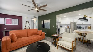 A modern living room with a sofa, a coffee table, and a dining area with chairs and a table. - 2 Mins to ASU, Swimming Pool, King Bed (Tempe)