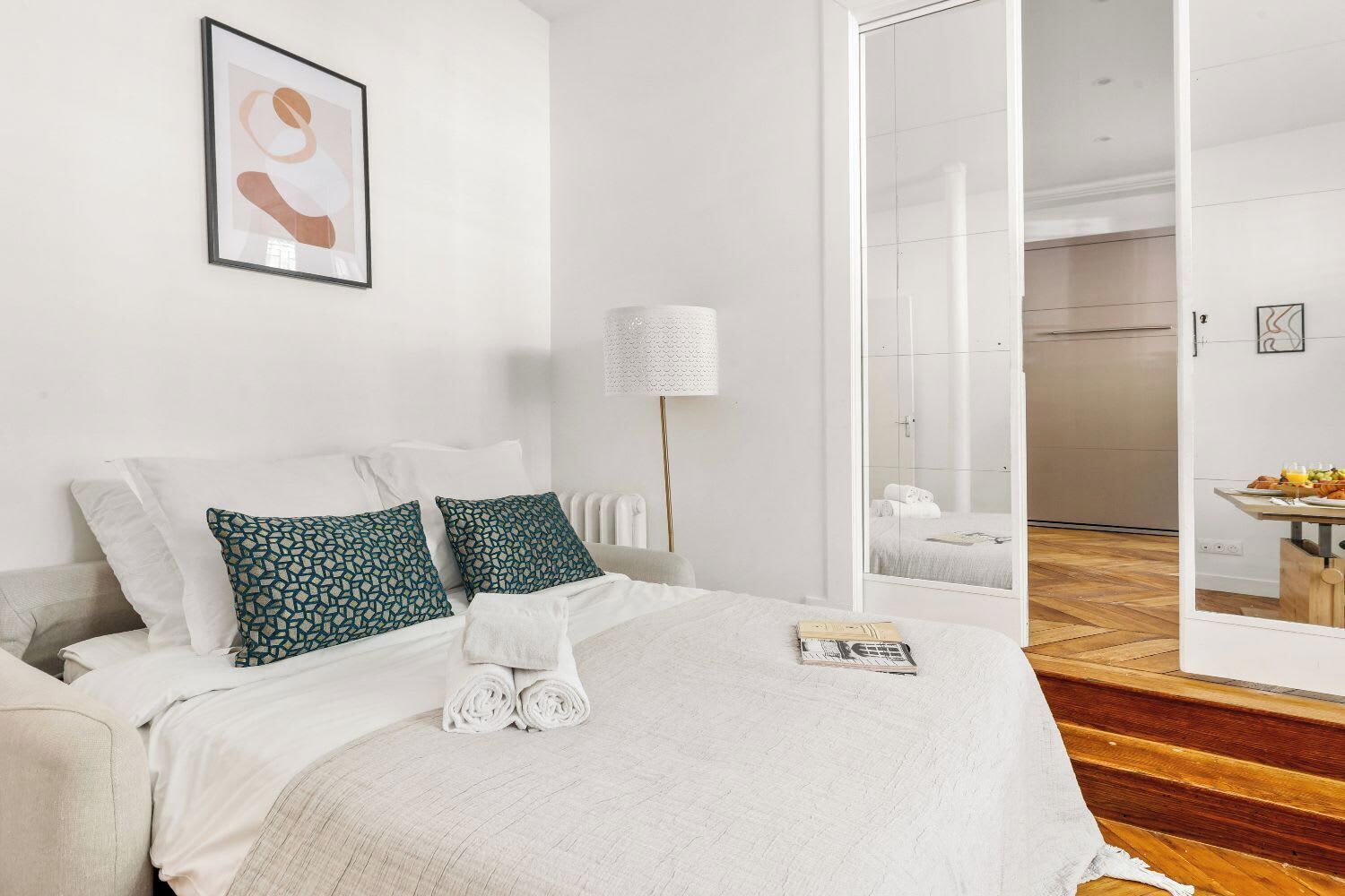 Een hotelkamer met een bed, nachtkastje, lamp en uitzicht op de badkamer door een geopende deur.