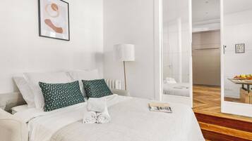 Een hotelkamer met een bed, nachtkastje, lamp en uitzicht op de badkamer door een geopende deur.
