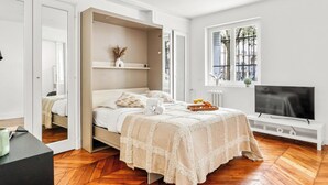 Ein Schlafzimmer mit Bett, Fernseher, Fenster mit Blick und Heizkörper.