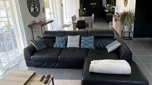 A modern living room with a black sectional sofa, a wooden coffee table, and a dining area with a table and chairs. - 🌿Very luminous villa near Uzès - peace & quiet 🌿 (Cavillargues)