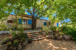 A stone building with blue shutters, a tree in front, and steps leading up to the entrance. - Holiday Home 'Lou Mazet Du Gaudon' with Shared Pool, Shared Terrace and Shared Garden (Montauroux)