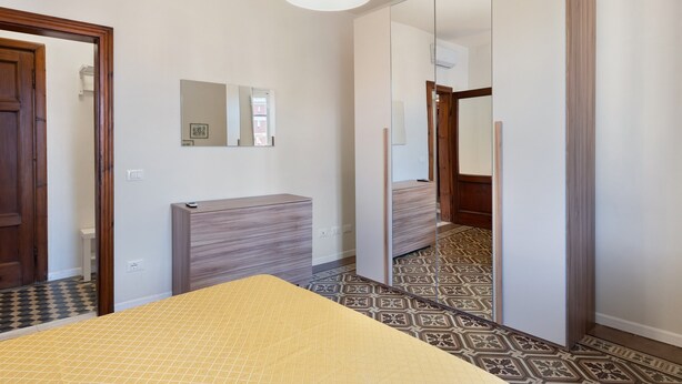 A hotel room with a bed, a bedside table, a mirror, and a wardrobe. - Holiday Home Armonia Lucca (Lucca)