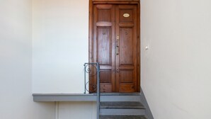 A wooden double door with a brass nameplate, a metal handrail, and a small light fixture on the wall. - Holiday Home Armonia Lucca (Lucca)