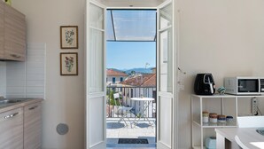 A compact kitchen with a dining area, a balcony with a view, and a small outdoor seating space. - Holiday Home Armonia Lucca (Lucca)