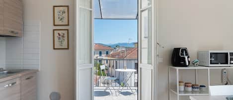 A compact kitchen with a dining area, a balcony with a view, and a small outdoor seating space.