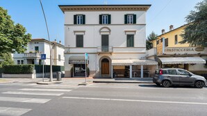 A street view with a building featuring a storefront labeled 'Pasticceria Belluomini' and a parked car. - Holiday Home Armonia Lucca (Lucca)