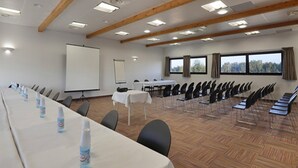 A conference room with a long table, chairs, a projector screen, and windows. - Spacious Coastal Stay for Six With AC (Le Grau-Du-Roi)