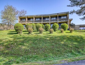 A multi-story building with a flat roof, surrounded by a well-maintained lawn and several small, rounded bushes. - Accessible Lake Stay for 4 in Miremont (Miremont)