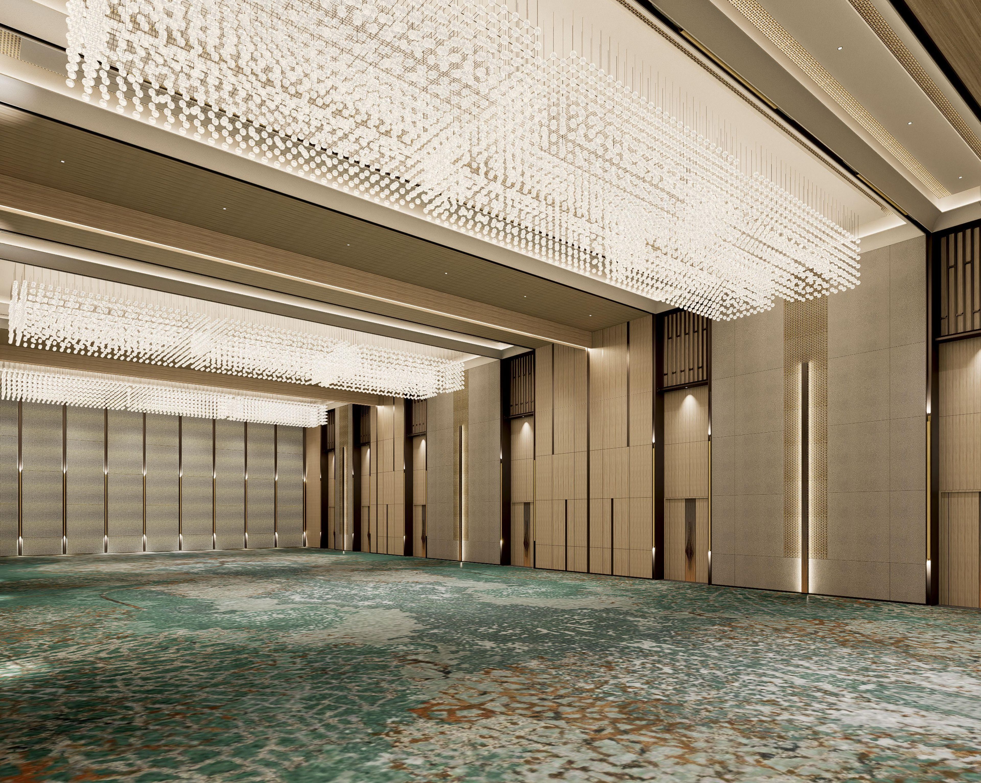 A spacious hotel lobby with a patterned carpet, high ceiling, and modern chandeliers.