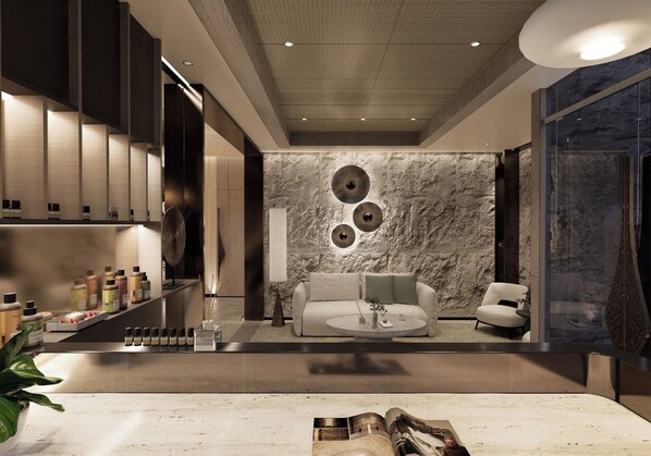 Una sala moderna con un sofá, sillones, una mesa de centro y una pared de piedra con decoración circular.
