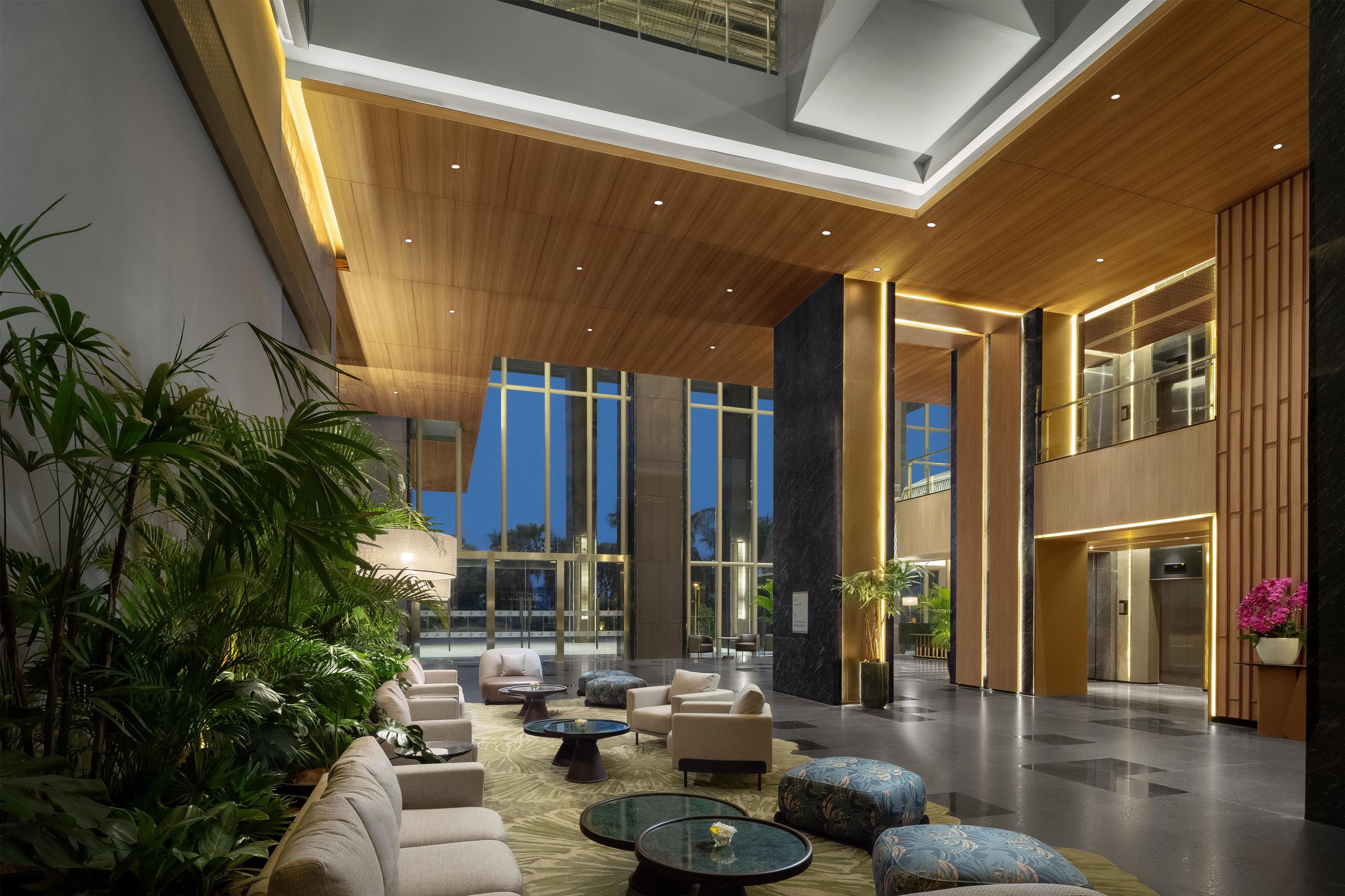 A spacious lobby with a high ceiling, modern furniture, and large windows.