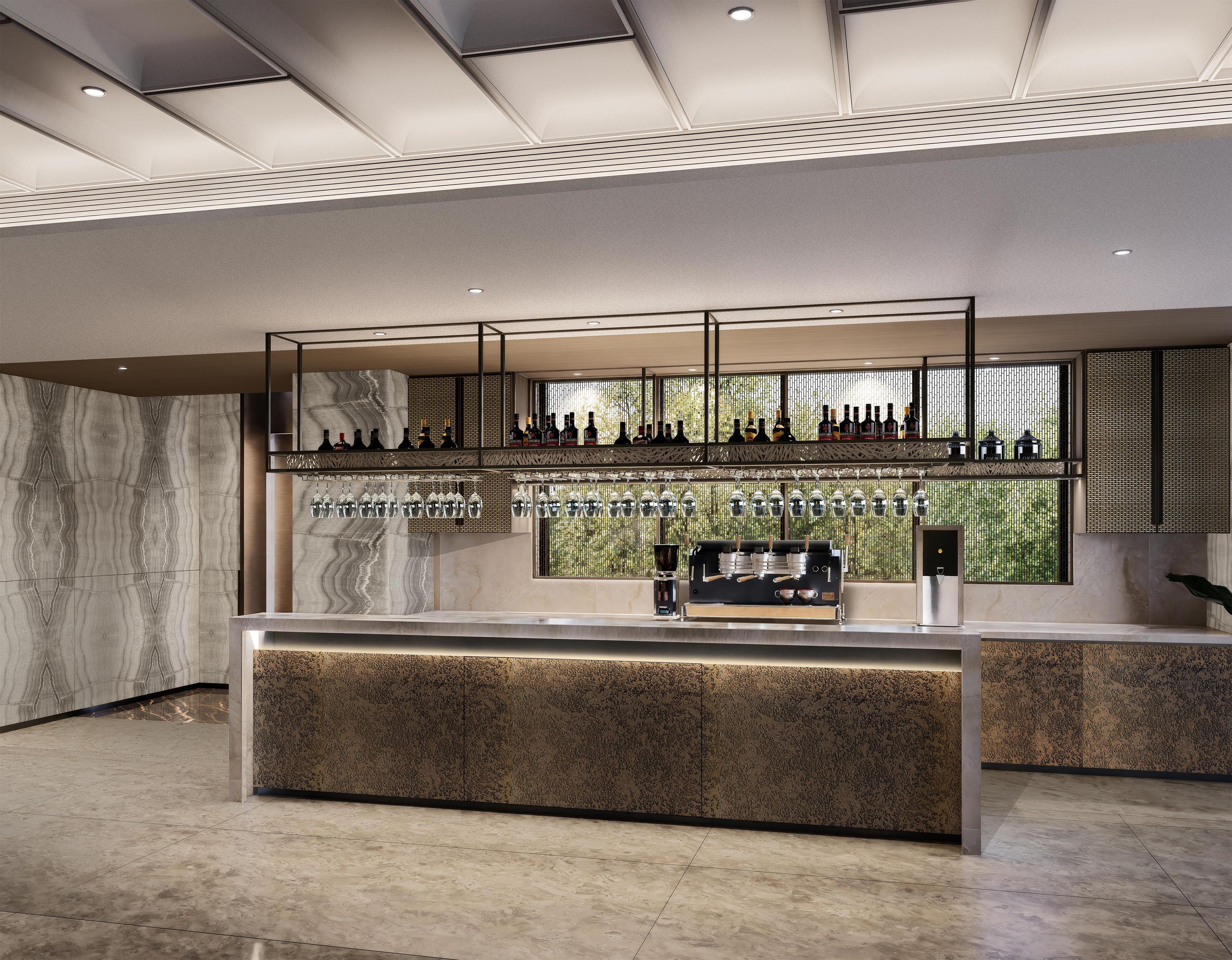A modern bar area with a marble countertop, a coffee machine, and a selection of bottles and glasses.