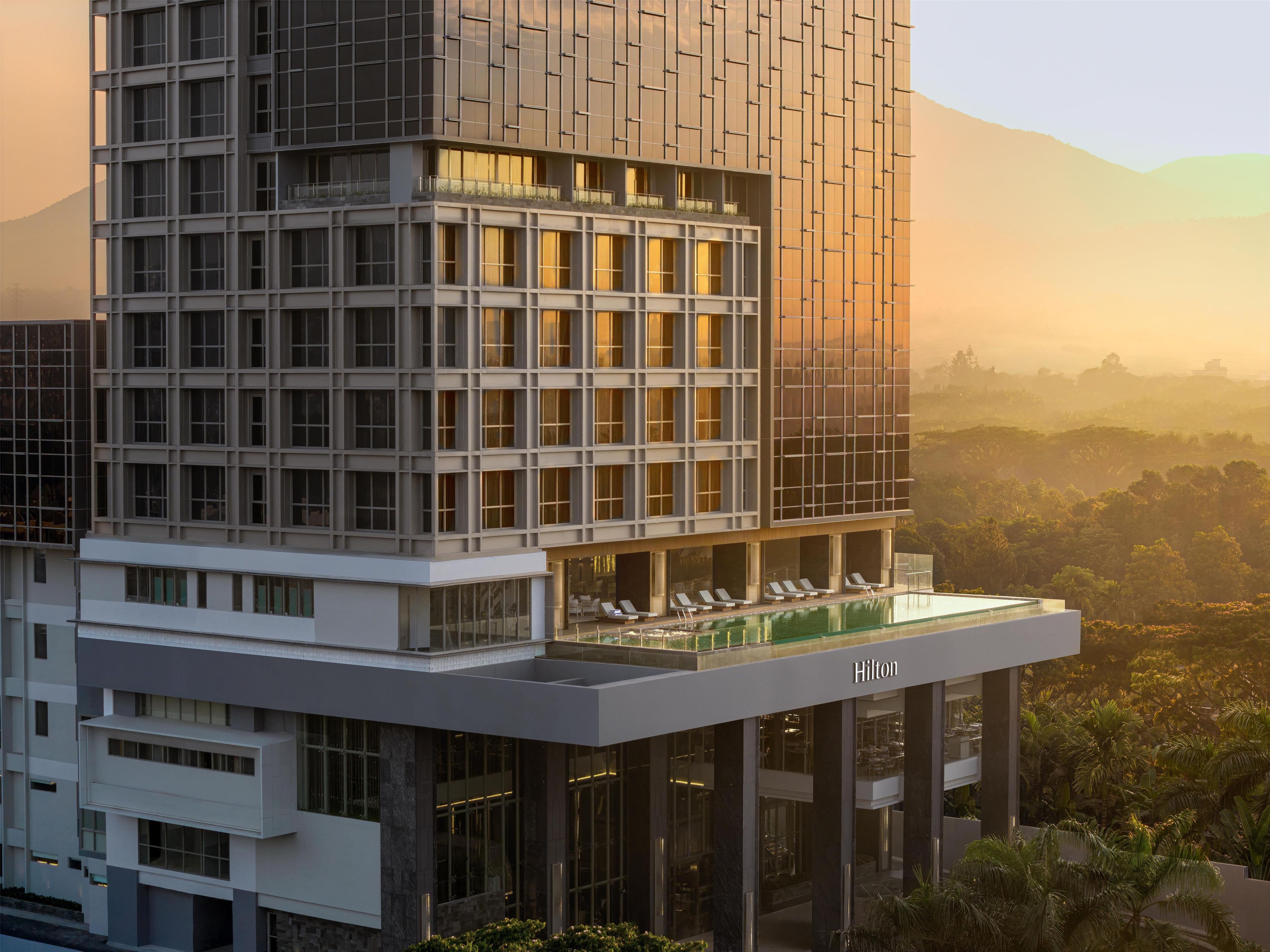 A modern hotel with a rooftop pool and a view of the surrounding landscape.