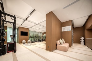 A modern gym with exercise equipment, a television, and a seating area with a wall-mounted sign. - Hilton Garden Inn Chongqing CBD Jiangbeizui (Chongqing)
