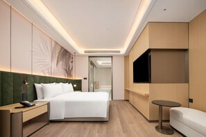 A hotel room with a bed, bedside table, TV, and a small round table. - Hilton Garden Inn Chongqing Jiangbeizui (Chongqing)