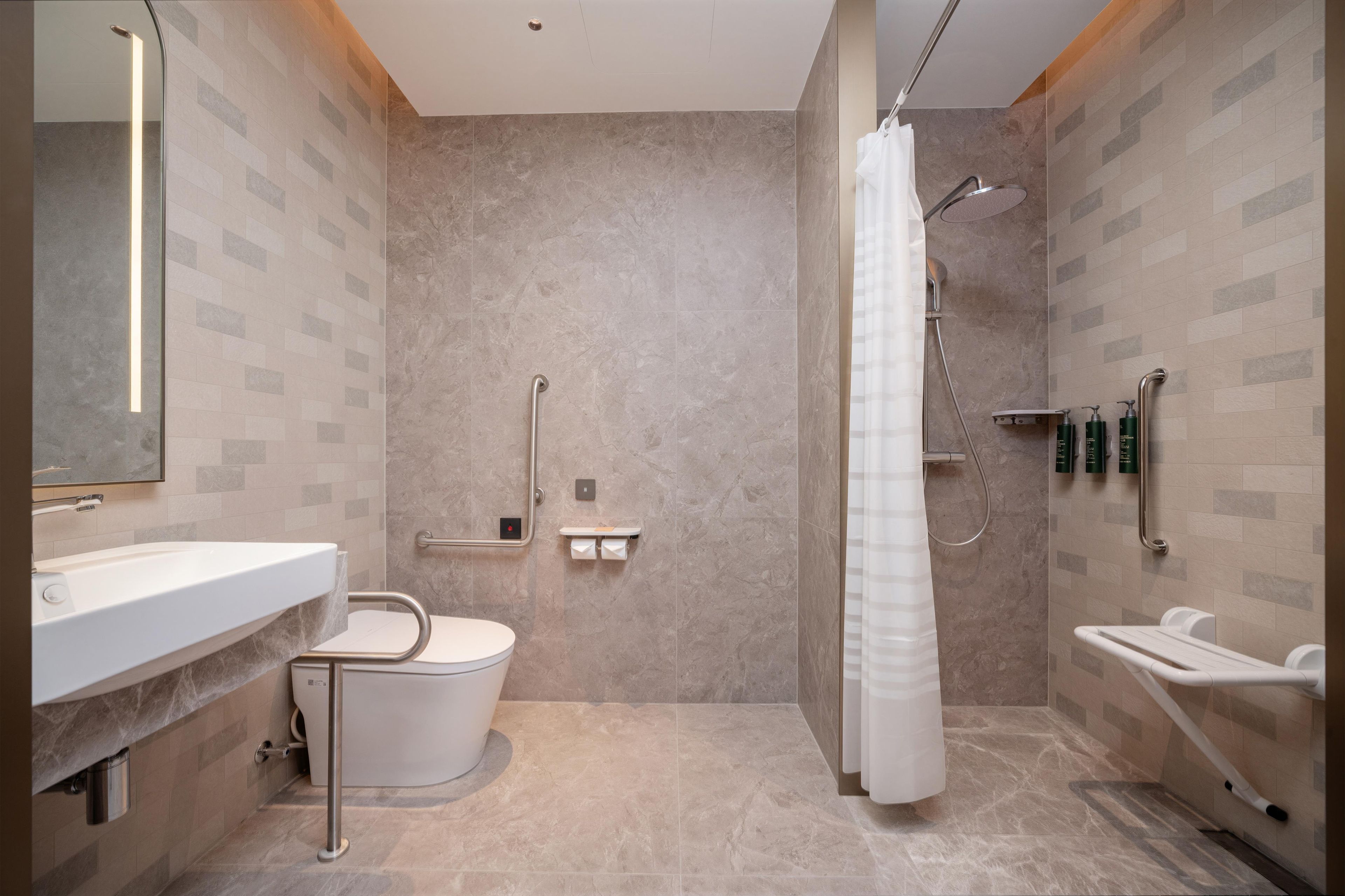 A modern bathroom with a shower, toilet, and sink, featuring a marble floor and wall tiles.