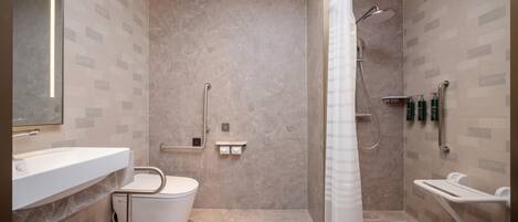 A modern bathroom with a shower, toilet, and sink, featuring a marble floor and wall tiles.