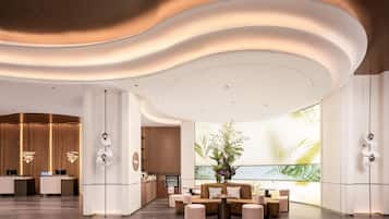 A modern hotel lobby with a reception desk, seating area, and a large window with a view.