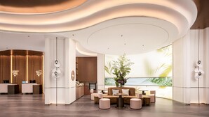 Een moderne hotellobby met een receptiebalie, een zithoek en een groot raam met uitzicht.