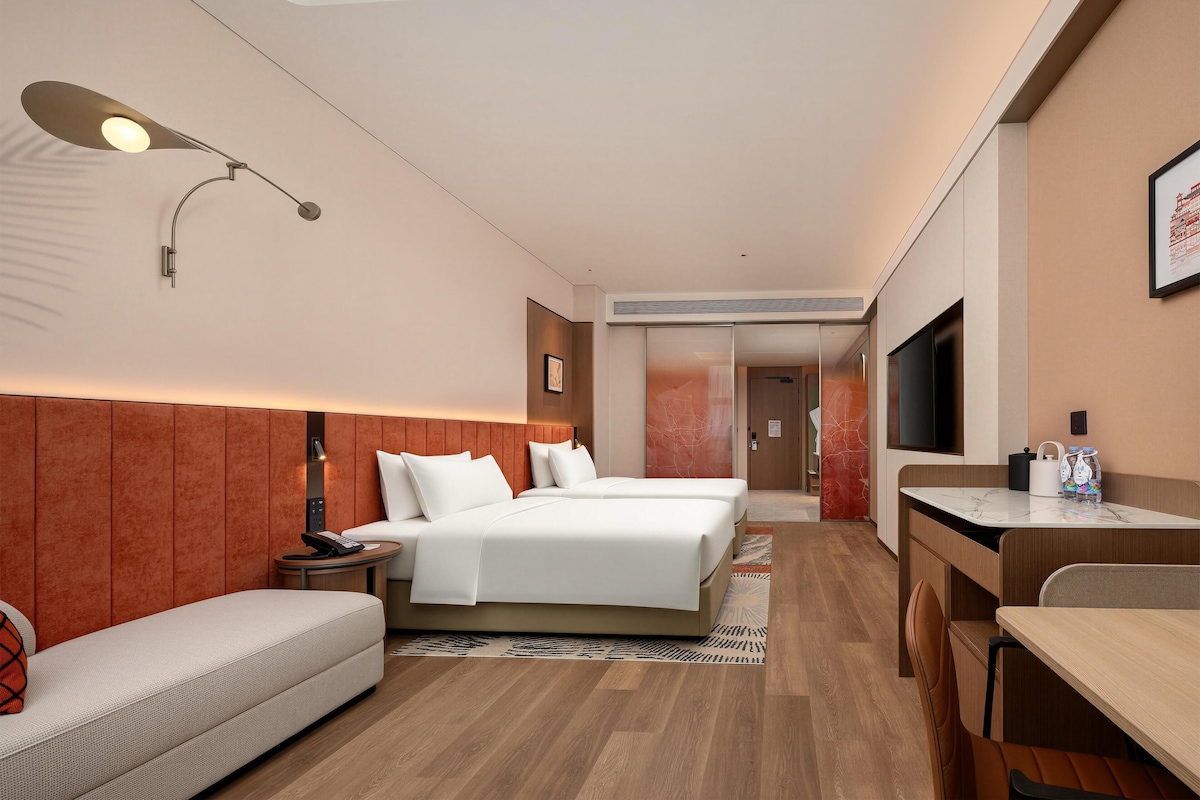 A hotel room with a bed, a sofa, a desk, and a TV.