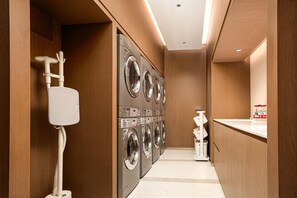 A laundry room with multiple washing machines, a water pump, and a small sink. - Hilton Garden Inn Chongqing Jiangbeizui (Chongqing)