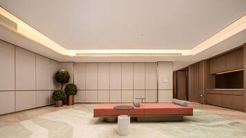 Un vestíbulo moderno con una zona de estar central, un mostrador de recepción y un televisor grande de pared.
