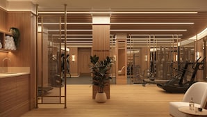 Un centre de remise en forme moderne doté d’un plancher en bois, d’équipements d’exercice et d’un comptoir d’accueil.