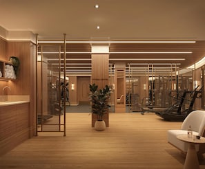 Un gimnasio moderno con suelo de madera, equipamiento de ejercicio y un mostrador de recepción.