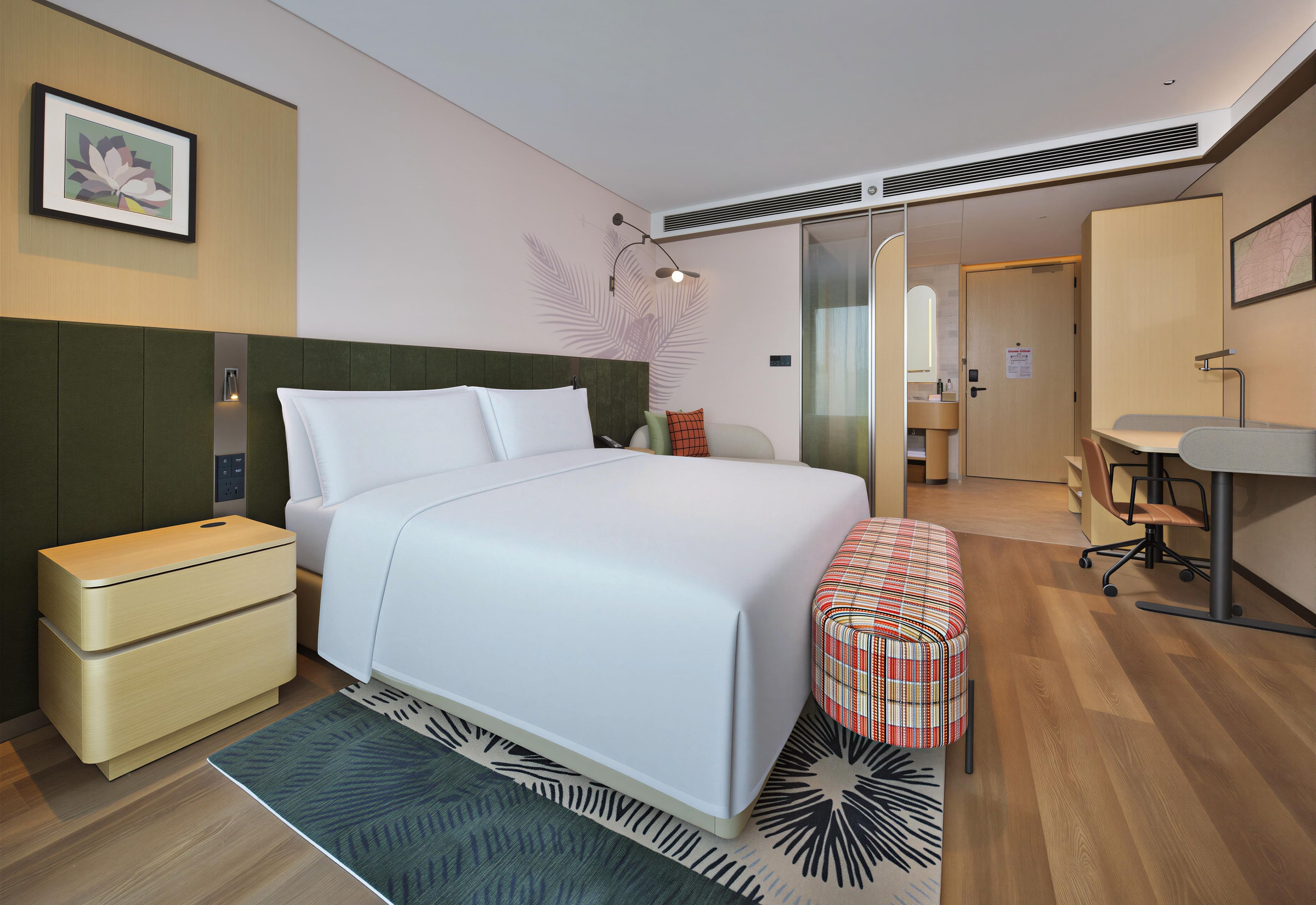 A modern hotel room with a bed, bedside tables, a desk, and a chair.