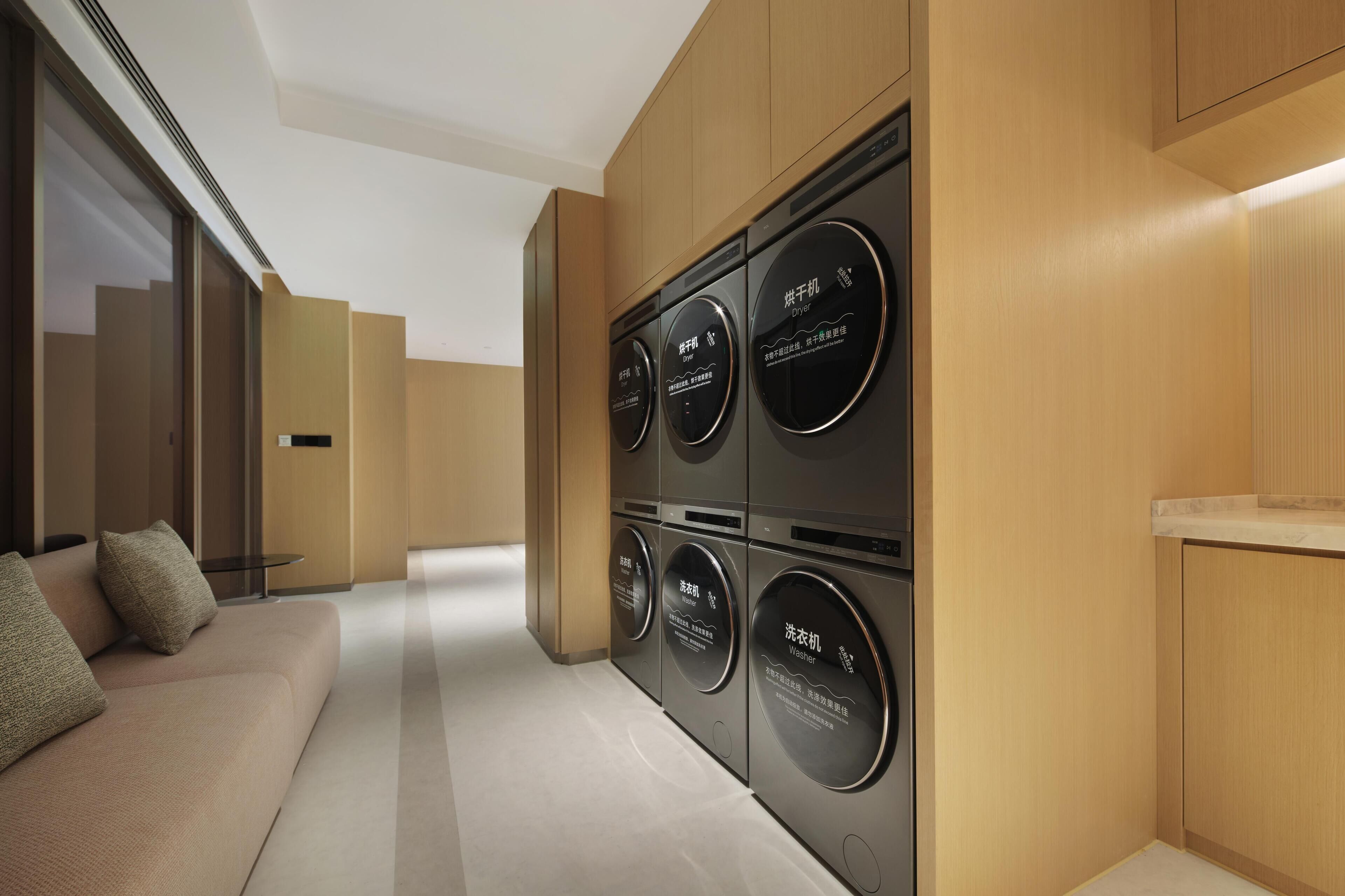 A modern hotel room with built-in appliances including a washer, dryer, and a small table.