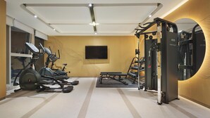 Un gimnasio con equipo de ejercicio, un televisor y un banco.