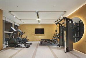 A gym with exercise equipment, a television, and a bench. - Hilton Garden Inn Shijiazhuang High-Tech Zone (Shijiazhuang)