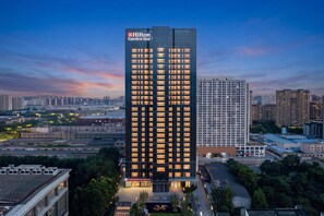 A high-rise hotel with a modern glass facade, multiple floors, and a prominent brand logo at the top. - Hilton Garden Inn Shijiazhuang High-Tech Zone (Shijiazhuang)