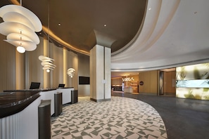 A hotel lobby with a reception desk, modern lighting fixtures, a patterned floor, and a bar area. - Hilton Garden Inn Shijiazhuang High-Tech Zone (Shijiazhuang)