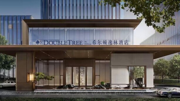 Entrada d'hotel amb un cartell de 'DOUBLETREE by Hilton' i un disseny modern.