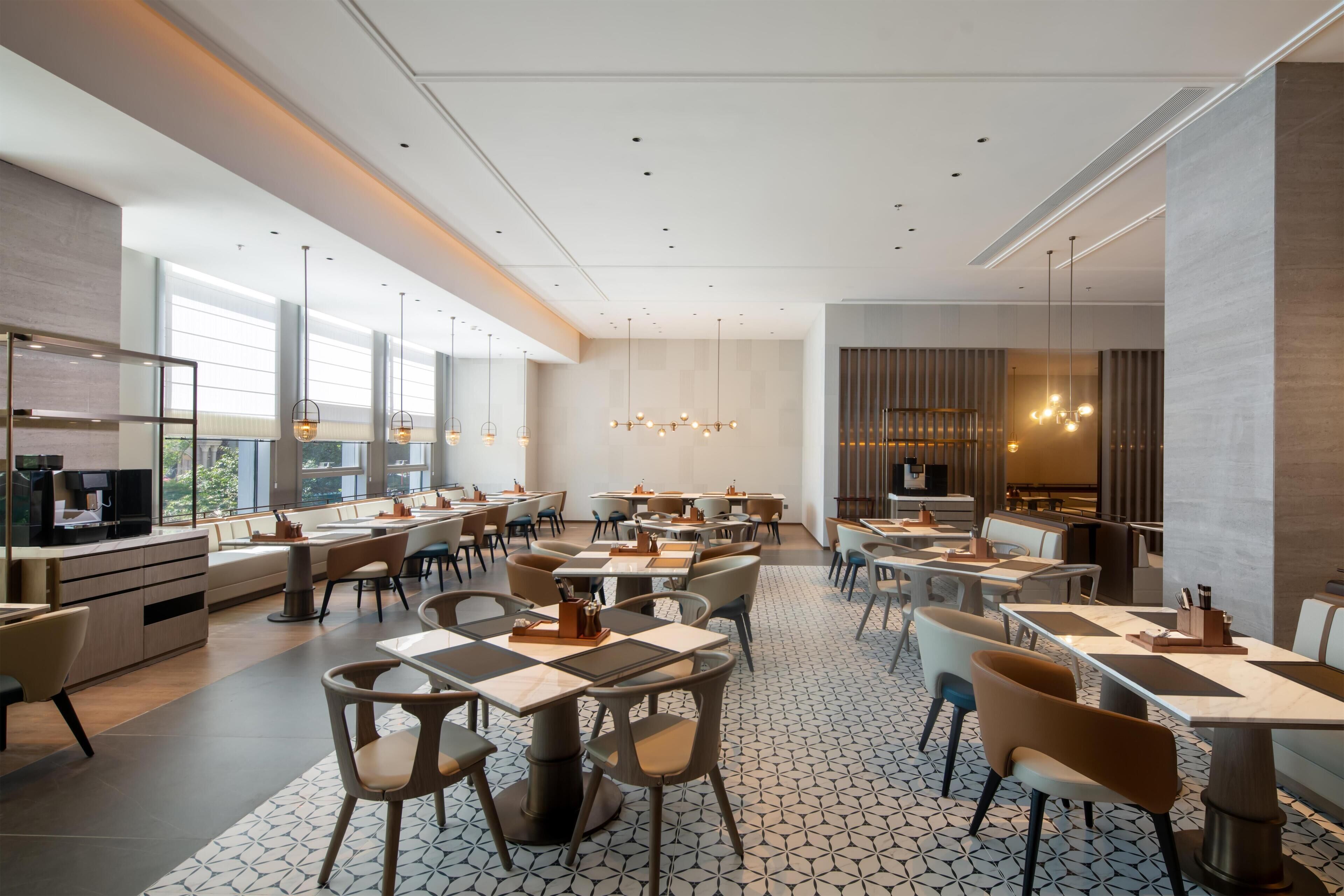 Un interior de restaurante moderno con techos altos, iluminación colgante y una combinación de mesas y cabinas.