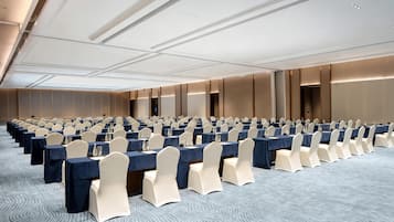 Un salón de conferencias con filas de mesas y sillas, equipado con botellas de agua y tarjetas de identificación.