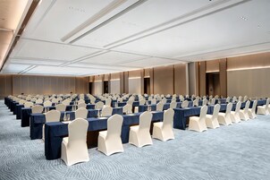 Un salón de conferencias con filas de mesas y sillas, equipado con botellas de agua y tarjetas de identificación.
