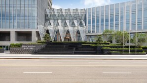 A modern hotel with a distinctive glass facade and a geometric sculpture in front. - Hilton Wenzhou (Wenzhou)