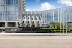 A modern hotel with a distinctive glass facade and a geometric sculpture in front. - Hilton Wenzhou (Wenzhou)