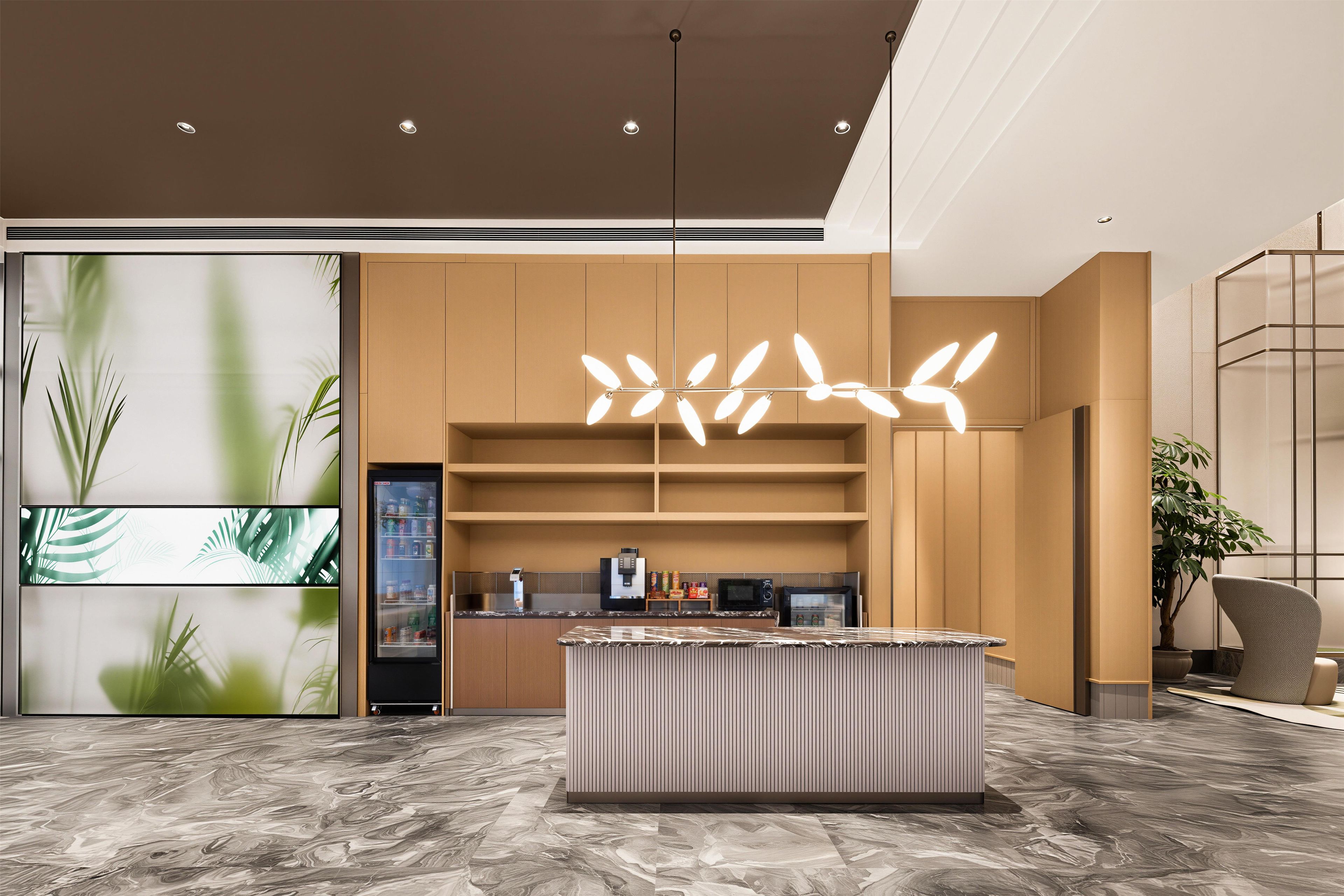 Un lobby moderno con piso de mármol, una isla central con cafetera y una pared grande con diseño de hojas.