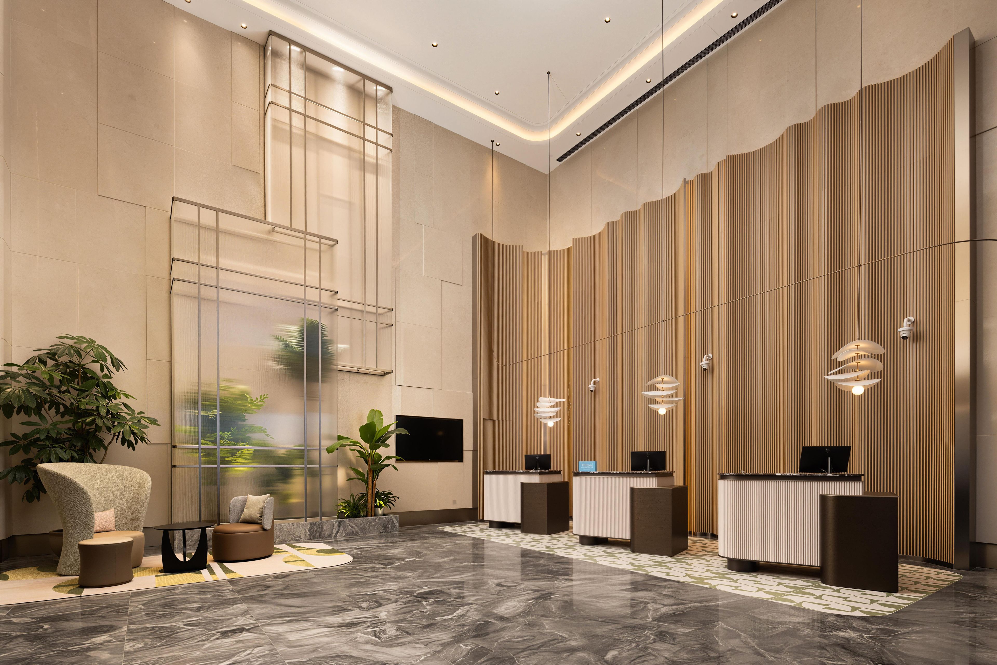 Um lobby moderno com balcão de recepção, área de estar e uma grande planta.