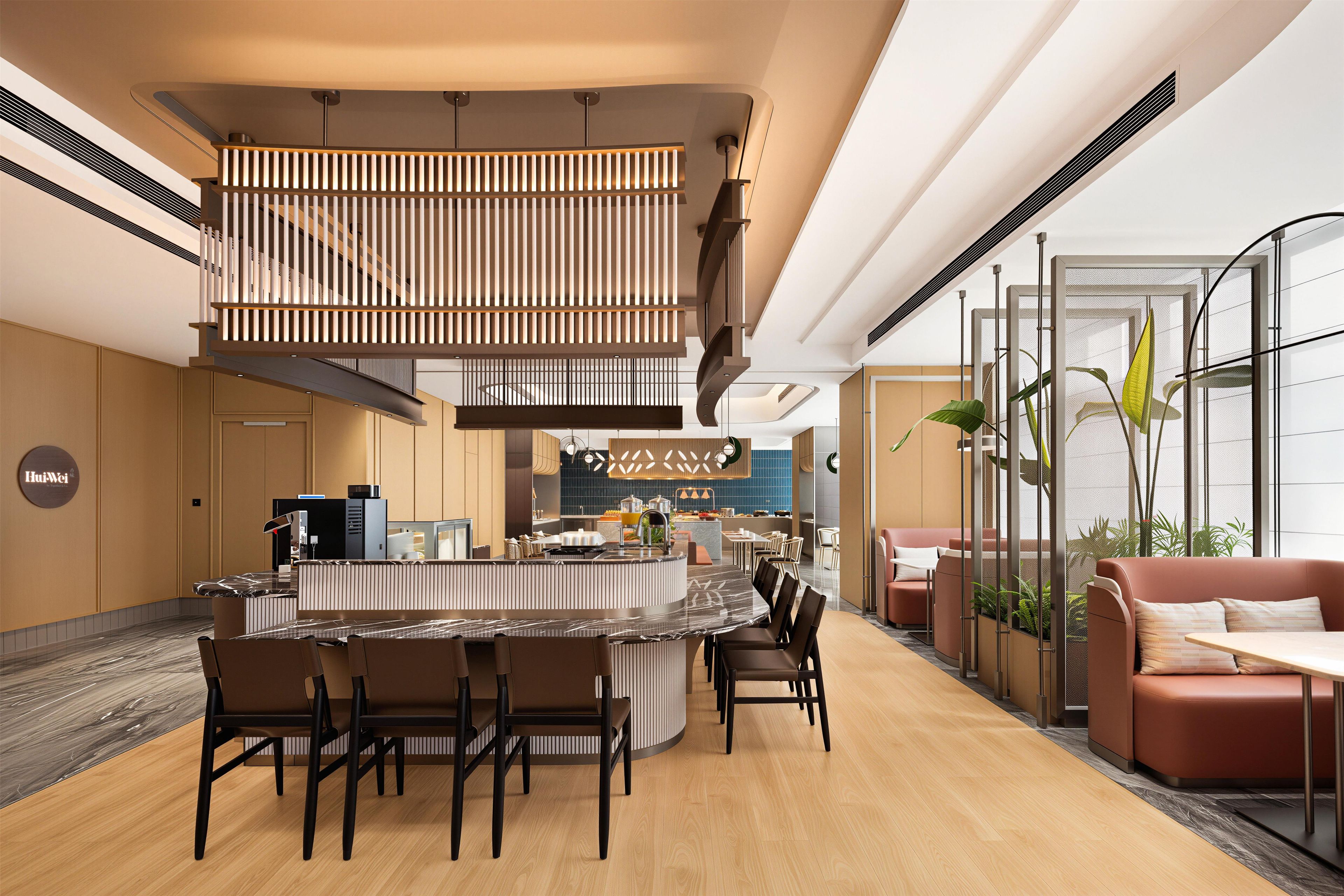 Un hall d’hôtel moderne doté d’un espace de restauration central, de différents types de sièges et d’une cuisine ouverte.