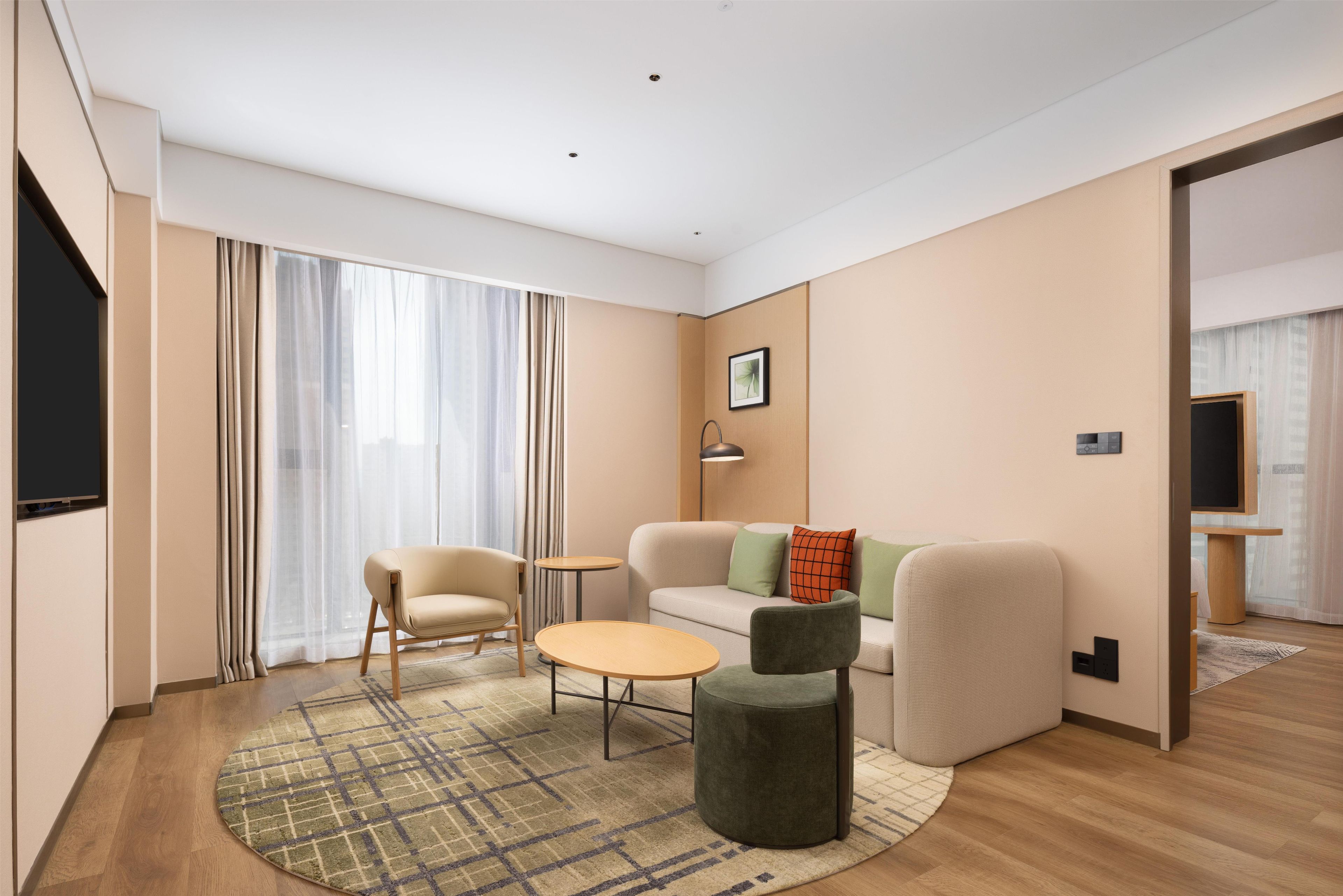 Una sala de estar moderna con un sofá, sillas, una mesa de centro y un televisor.