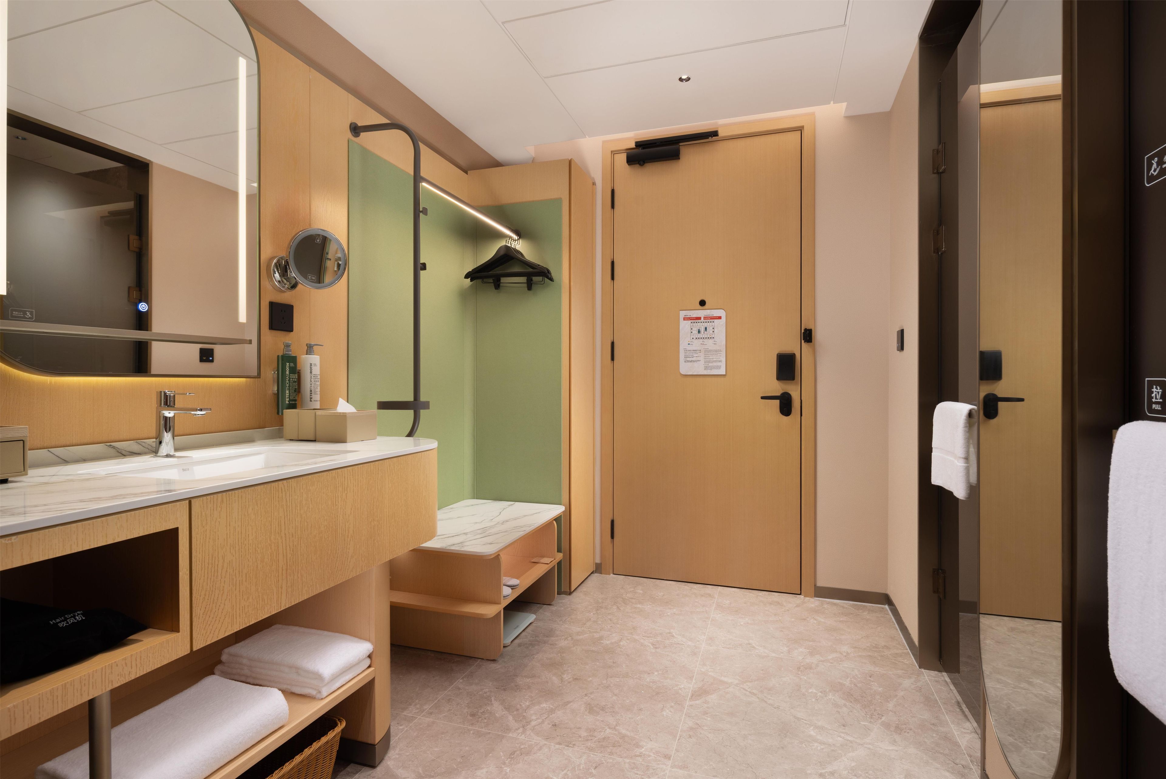 Une salle de bain d’hôtel équipée d’un lavabo, d’un miroir, d’un porte-serviettes et d’une porte avec une pancarte.