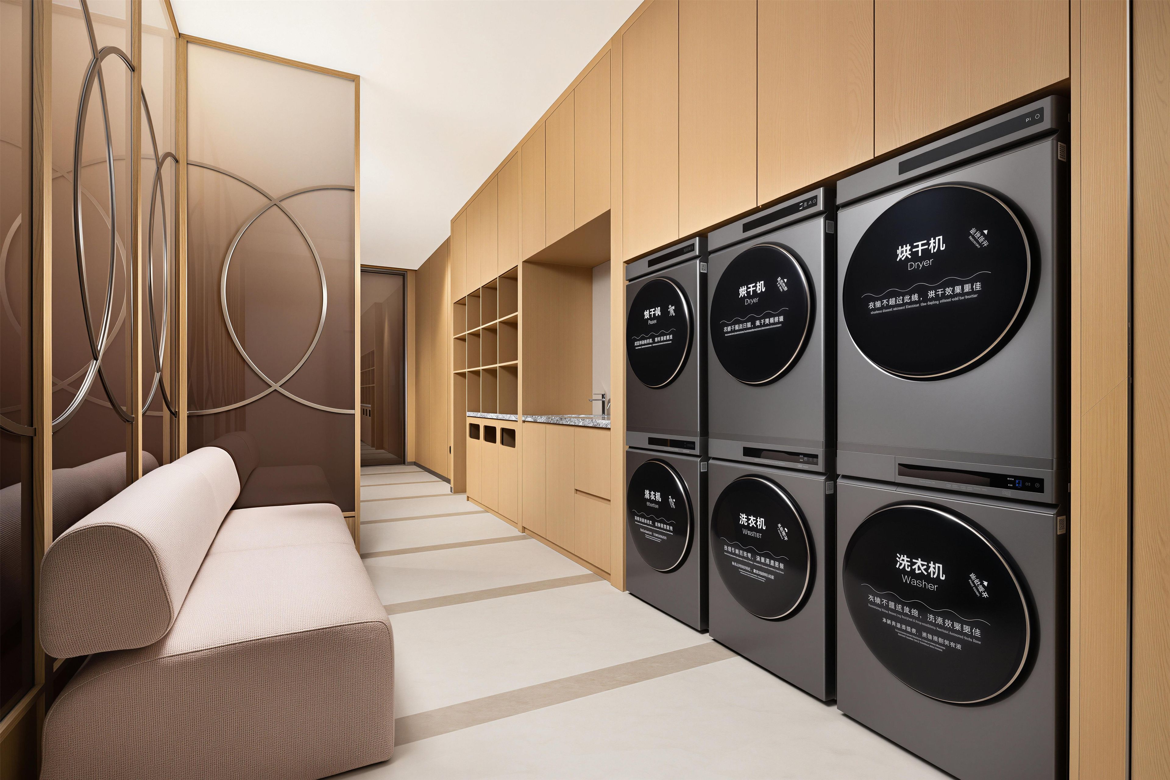Un moderno cuarto de lavado con lavadoras y secadoras empotradas, una zona de estar con sofá y un elemento decorativo circular en la pared.