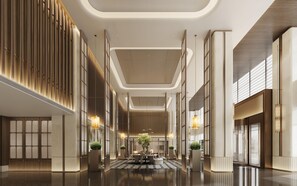 En rummelig lobby med et centralt siddeområde, høje lofter og moderne lysarmaturer.